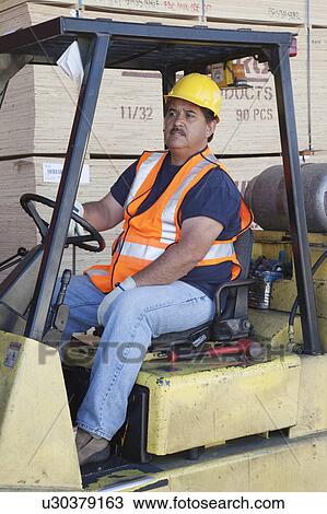 Stock Image - Forklift driver driving in warehouse. Fotosearch