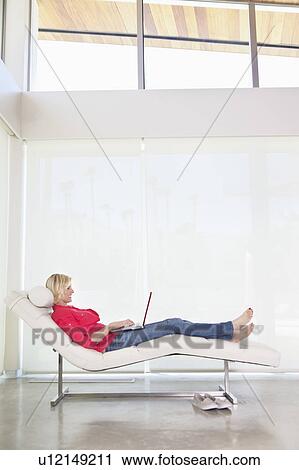 Full length of woman lying on deck chair with laptop View Large Photo Image Stock Image - Full length of woman lying on deck chair with laptop. Fotosearch