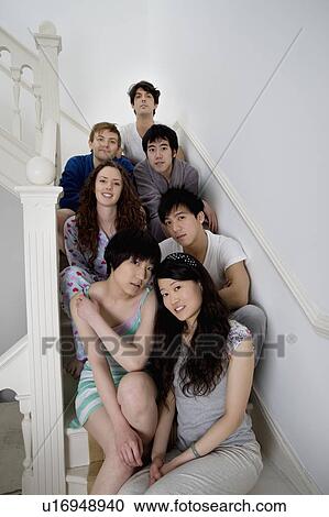 Stock Image - Group portrait of friends sitting in stairway. Fotosearch