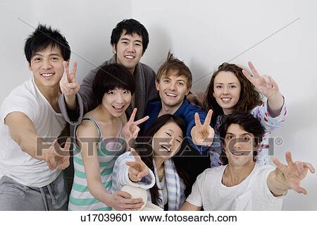 Stock Image - Group portrait of young friends showing peace sign. Fotosearch
