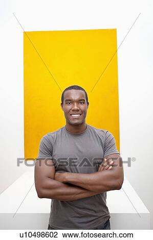 Stock Image - Half-length portrait of smiling young man in front of painting. Fotosearch