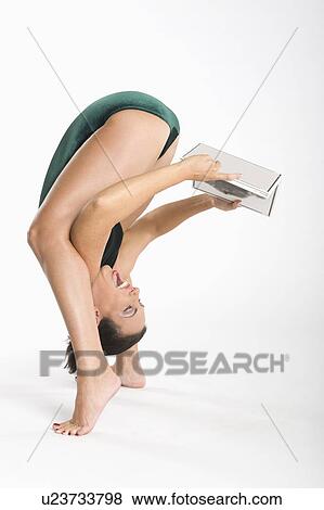 Laughing woman holding book while exercising View Large Photo Image Stock Photo - Laughing woman holding book while exercising. Fotosearch