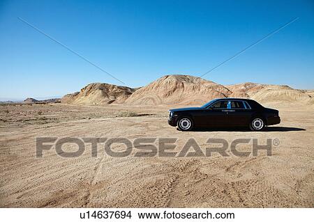 Luxury car parked on unpaved road near mountains View Large Photo Image Picture - Luxury car parked on unpaved road near mountains. Fotosearch