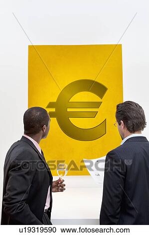 Male executive looking at Euro sign over white background View Large Photo Image Stock Image - Male executive looking at Euro sign over white background. Fotosearch