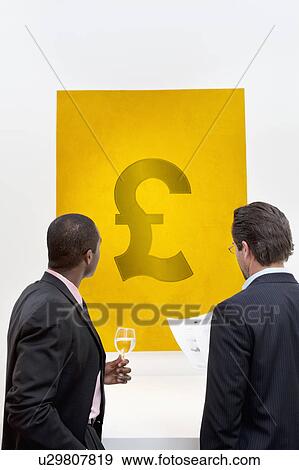 Stock Photo - Male executive looking at Pound sign over white background. Fotosearch