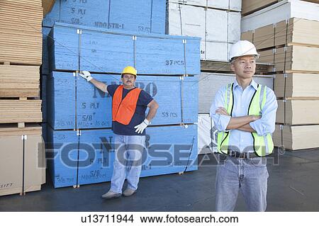 Male warehouse workers standing in front of stack of plywood View Large Photo Image Picture - Male warehouse workers standing in front of stack of plywood. Fotosearch