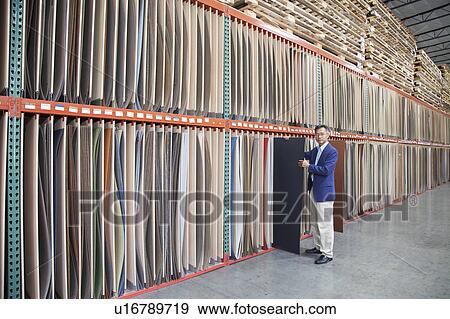 Stock Photo - Manager holding plywood in warehouse. Fotosearch