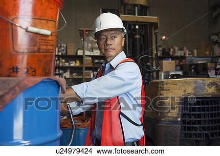 Picture - Middle-aged manager looking at something in warehouse. Fotosearch