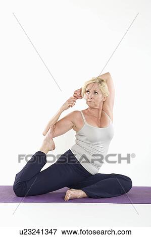 Middle aged woman doing stretching on yoga mat over white background View Large Photo Image Stock Photo - Middle aged woman doing stretching on yoga mat over white background. Fotosearch
