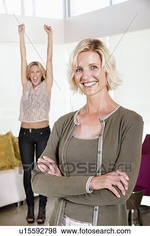 Mother smiling in front of excited daughter with hands raised View Large Photo Image Stock Photo - Mother smiling in front of excited daughter with hands raised. Fotosearch