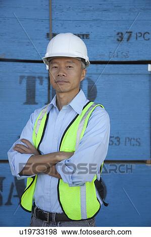 Portrait of a middle-aged warehouse worker standing with arms crossed View Large Photo Image Stock Photo - Portrait of a middle-aged warehouse worker standing with arms crossed. Fotosearch