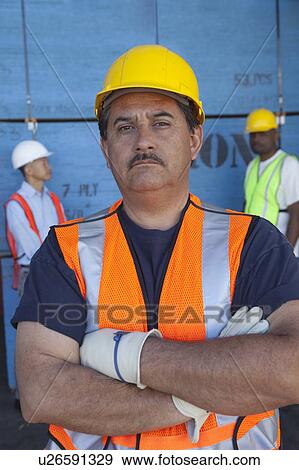 Portrait of confident middle-aged man with colleagues in background View Large Photo Image Stock Photo - Portrait of confident middle-aged man with colleagues in background. Fotosearch