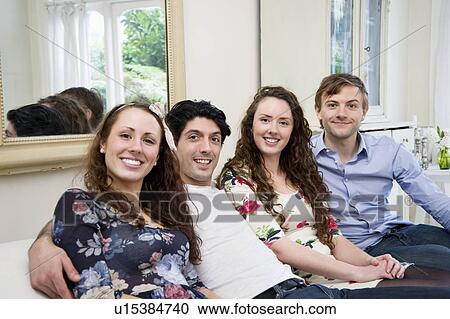 Stock Image - Portrait of friends sitting on sofa. Fotosearch