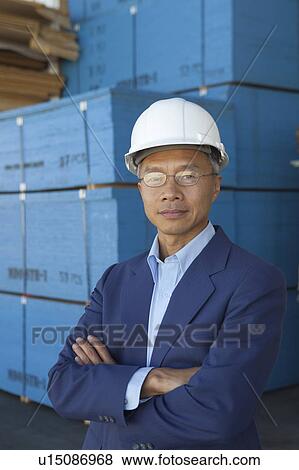 Stock Photo - Portrait of manager wearing hard hat with arms crossed. Fotosearch
