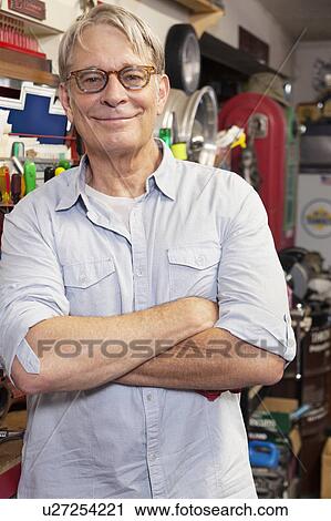 Stock Image - Portrait of smiling senior man with glasses and arms crossed. Fotosearch