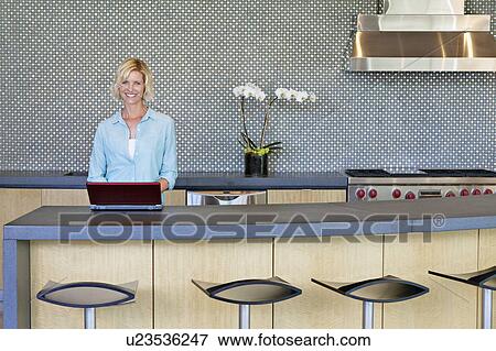 Portrait of smiling senior woman using laptop in kitchen View Large Photo Image Stock Photo - Portrait of smiling senior woman using laptop in kitchen. Fotosearch