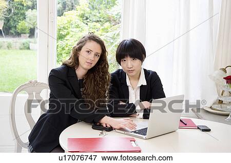 Stock Photo - Portrait of two business woman using laptop. Fotosearch