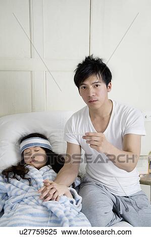 Portrait of young man while woman lying in bed View Large Photo Image Stock Photography - Portrait of young man while woman lying in bed. Fotosearch