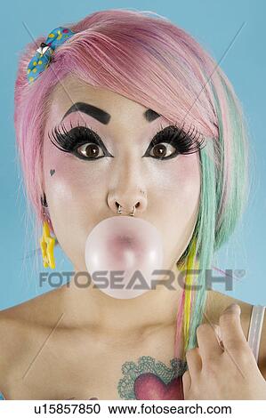 Stock Image - Portrait of young woman blowing bubble gum. Fotosearch