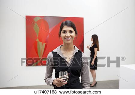 Portrait of young woman in front of painting in art gallery View Large Photo Image Stock Photo - Portrait of young woman in front of painting in art gallery. Fotosearch
