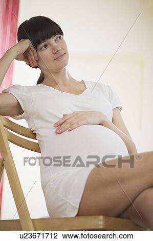 Pregnant woman sitting on chair and looking away View Large Photo Image Stock Image - Pregnant woman sitting on chair and looking away. Fotosearch