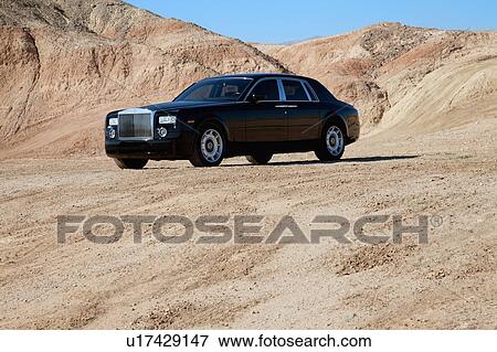 Stock Photo - Rolls Royce car parked on unpaved road with mountains in background. Fotosearch