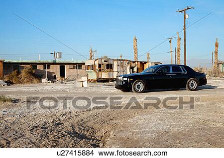 Picture - Rolls Royce parked in front of abandoned houses. Fotosearch
