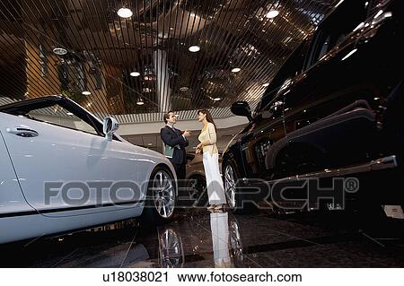 Salesman talking to woman in automobile showroom View Large Photo Image Stock Image - Salesman talking to woman in automobile showroom. Fotosearch