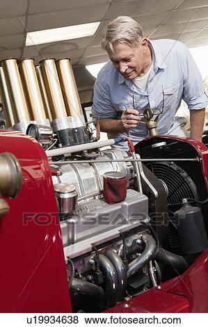 Stock Photo - Senior man looking at car engine in automobile repair shop. Fotosearch