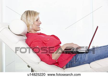 Senior woman lying on chair with laptop View Large Photo Image Stock Image - Senior woman lying on chair with laptop. Fotosearch