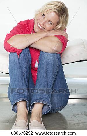 Stock Image - Senior woman sitting on floor. Fotosearch