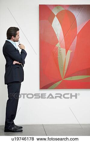 Stock Photo - Side view of a man looking intensely towards painting. Fotosearch