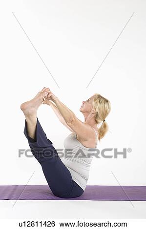 Side view of a woman doing yoga View Large Photo Image Stock Photograph - Side view of a woman doing yoga. Fotosearch