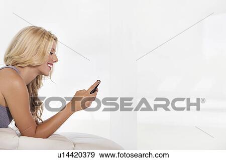Side view of beautiful young woman reading text message on cell phone View Large Photo Image Stock Photo - Side view of beautiful young woman reading text message on cell phone. Fotosearch