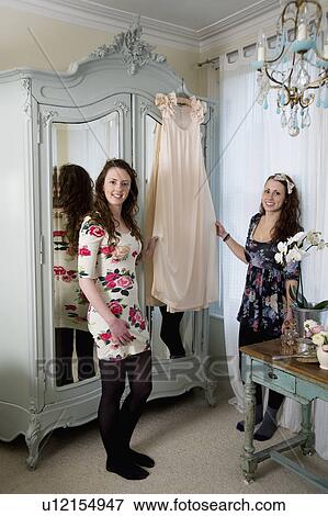 Sisters holding dress hanged on hanger View Large Photo Image Stock Photo - Sisters holding dress hanged on hanger. Fotosearch