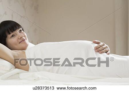Smiling pregnant woman lying on bed View Large Photo Image Stock Image - Smiling pregnant woman lying on bed. Fotosearch