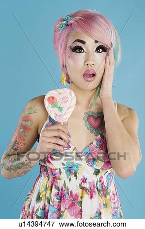 Surprised young woman holding heart shaped candy View Large Photo Image Stock Photo - Surprised young woman holding heart shaped candy. Fotosearch