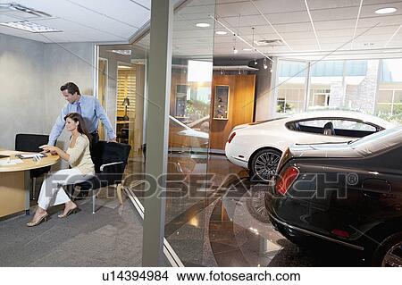 Woman and salesman sitting in car showroom office View Large Photo Image Picture - Woman and salesman sitting in car showroom office. Fotosearch