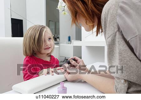 Stock Photo - Woman applying nail polish on little girl's hand. Fotosearch