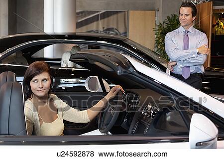 Woman having a test drive while salesperson standing besides car View Large Photo Image Stock Photo - Woman having a test drive while salesperson standing besides car. Fotosearch