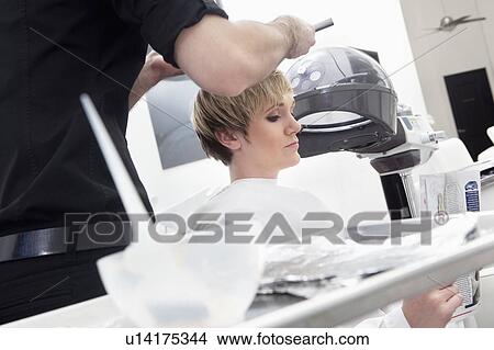Woman reading magazine while hairdresser coloring hair View Large Photo Image Picture - Woman reading magazine while hairdresser coloring hair. Fotosearch