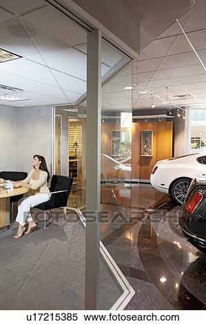 Stock Photography - Woman sitting in car showroom office. Fotosearch