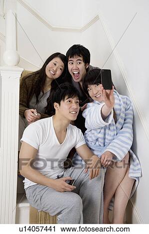 Stock Image - Young couples taking self portrait photographs on stairway. Fotosearch