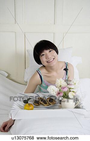 Young female having breakfast in bed View Large Photo Image Stock Photo - Young female having breakfast in bed. Fotosearch