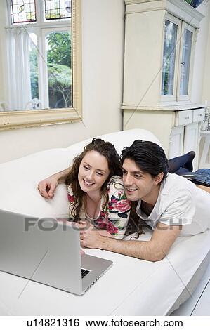 Young happy couple sharing laptop on sofa View Large Photo Image Stock Photograph - Young happy couple sharing laptop on sofa. Fotosearch