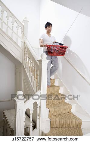 Stock Photo - Young man carrying a laundry basket of clothes. Fotosearch