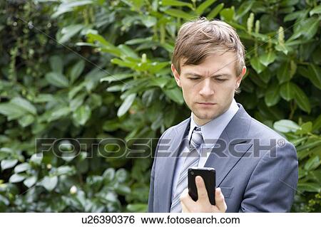 Stock Photograph - Young man looking at mobile phone. Fotosearch