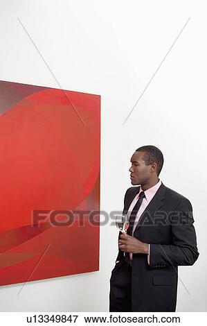 Young man looking at wall painting in art gallery View Large Photo Image Stock Photo - Young man looking at wall painting in art gallery. Fotosearch