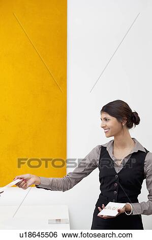 Young receptionist giving away templates View Large Photo Image Stock Photograph - Young receptionist giving away templates. Fotosearch