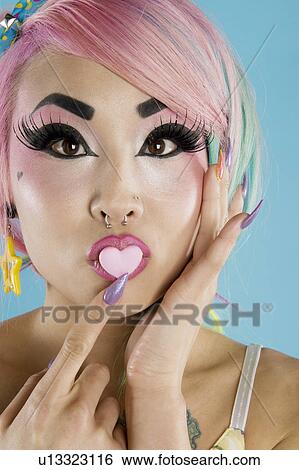 Young woman holding a heart shaped candy on her lips View Large Photo Image Stock Photograph - Young woman holding a heart shaped candy on her lips. Fotosearch